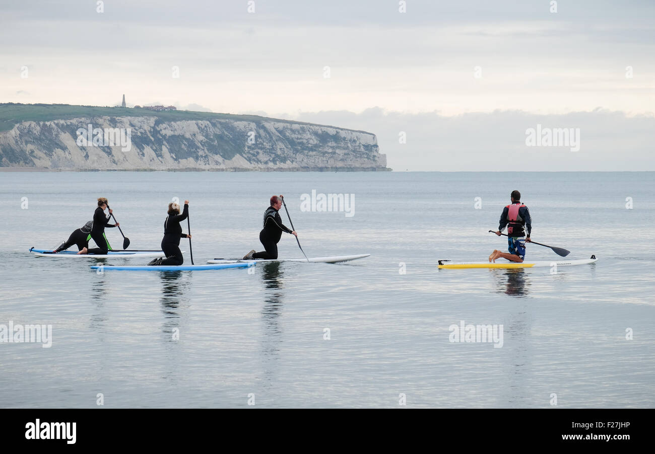 A group of paddle boarders heading out into the calm waters of Sandown Bay Stock Photo