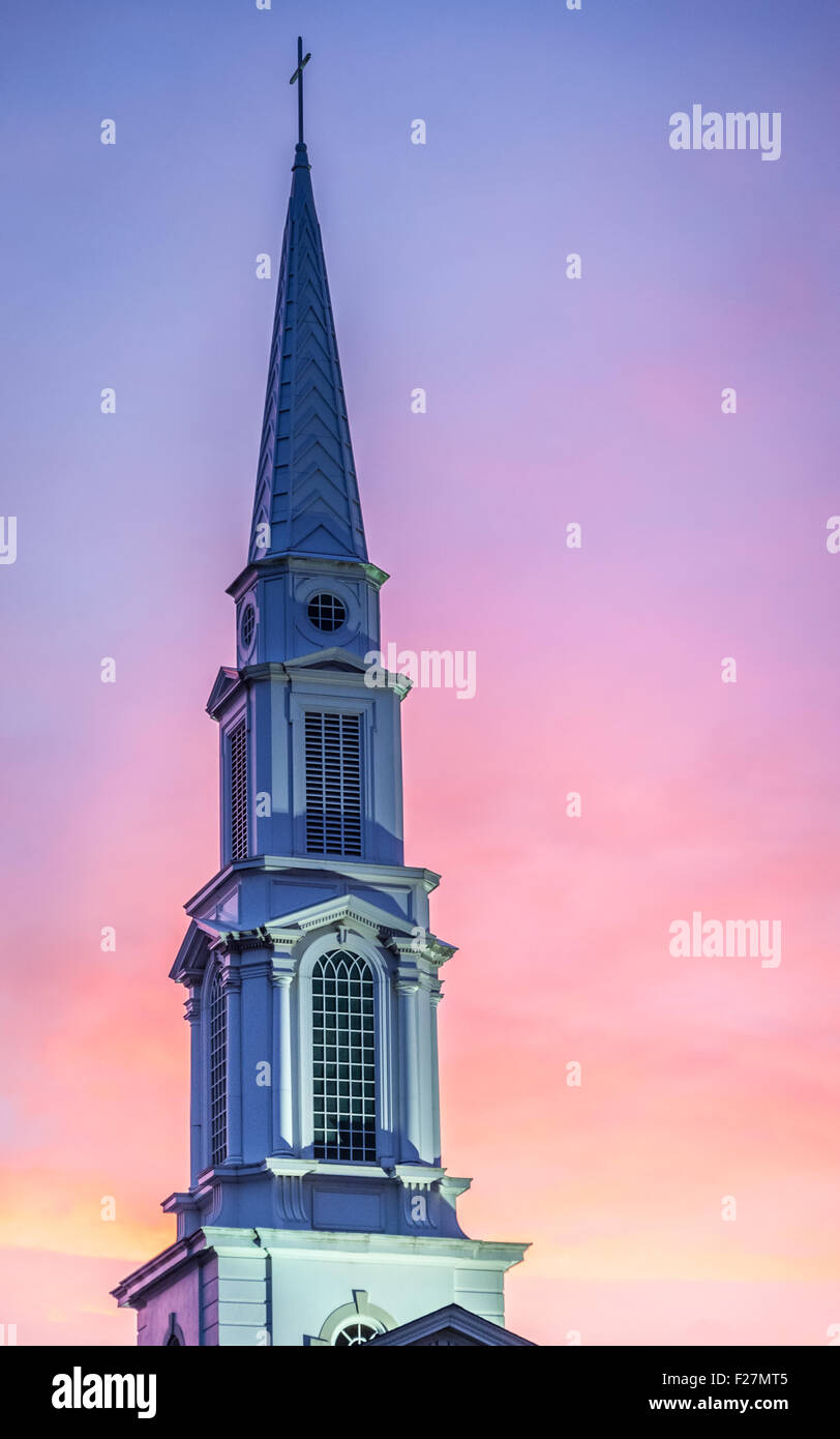 Large, white, church steeple against a colorful sunset sky. Stock Photo