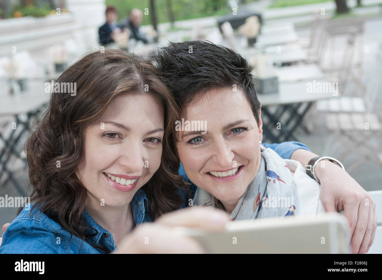 Two friends make selfy in the sidewalk cafe, Bavaria, Germany Stock Photo