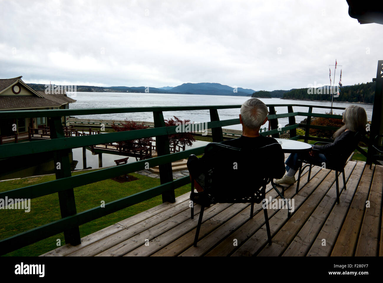 Couple sitting on sundeck looking over Discovery Passage April Point Resort Quadra Island BC Canada Stock Photo