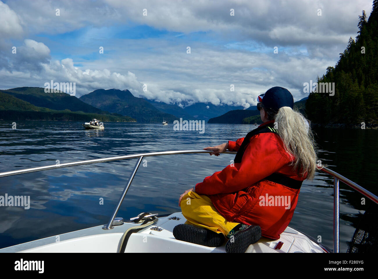 Female angler enjoying view sitting on bow of boat Davis Point Thurston Bay Campbell River BC Canada Stock Photo