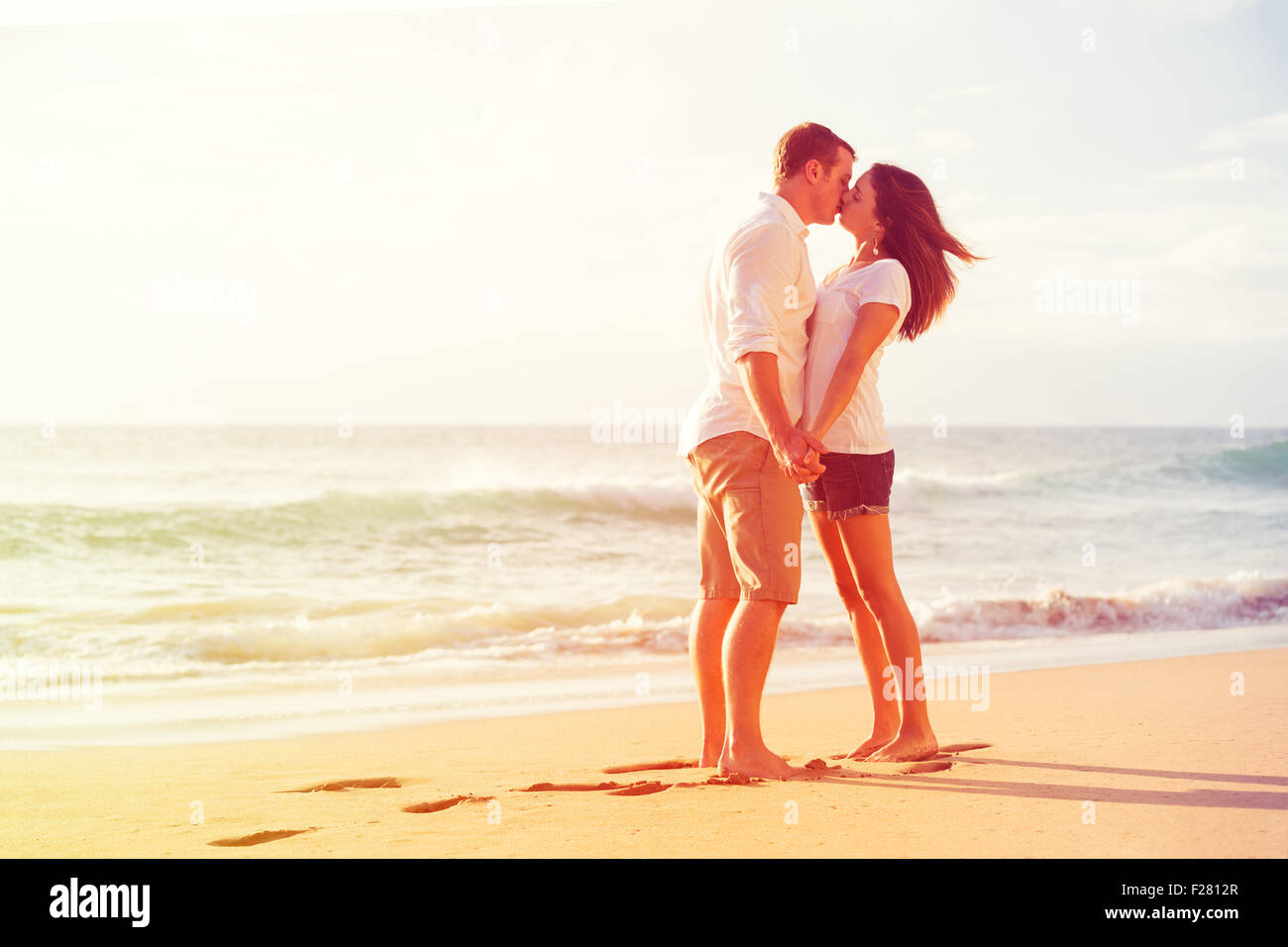 Happy Romantic Couple Kissing on the Beach at Sunset Stock Photo - Alamy