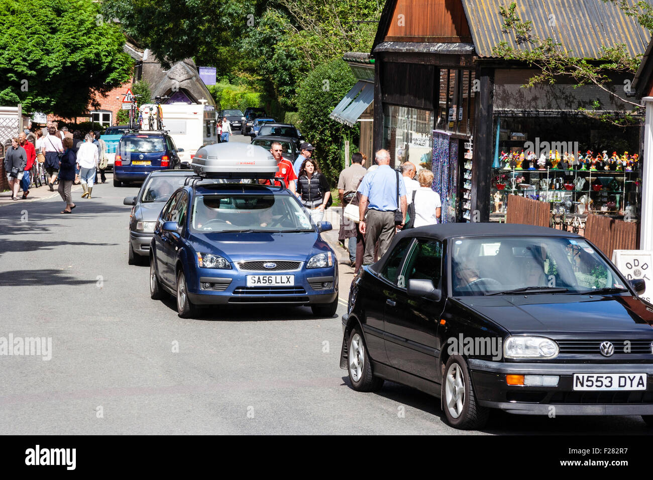 England, New Forest, Town of Burley. View along busy street with tourists on pavement and line of cars stuck in summer traffic congestion. Stock Photo