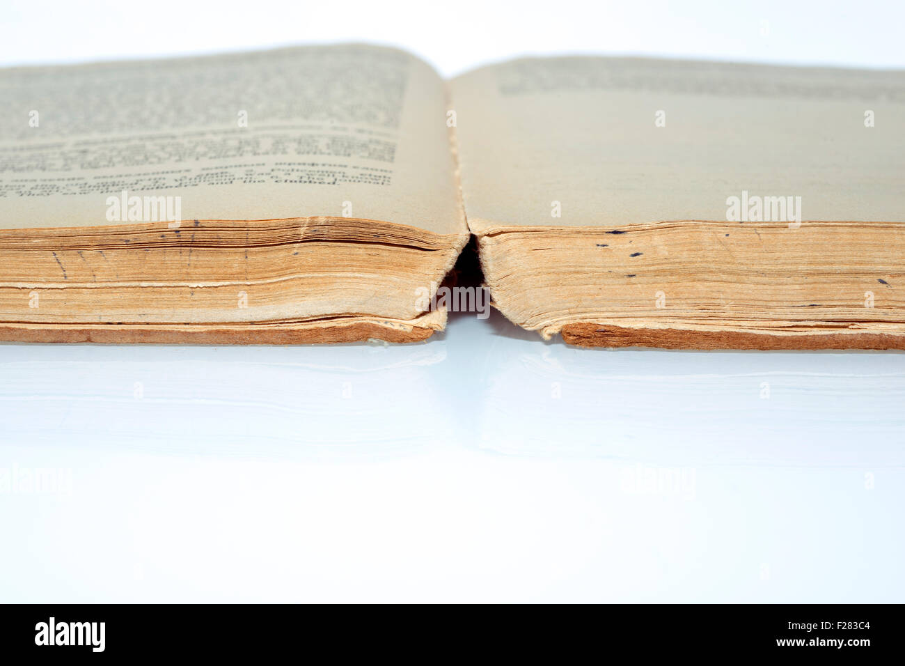 yellowish ancient book open on the white reflective surface Stock Photo