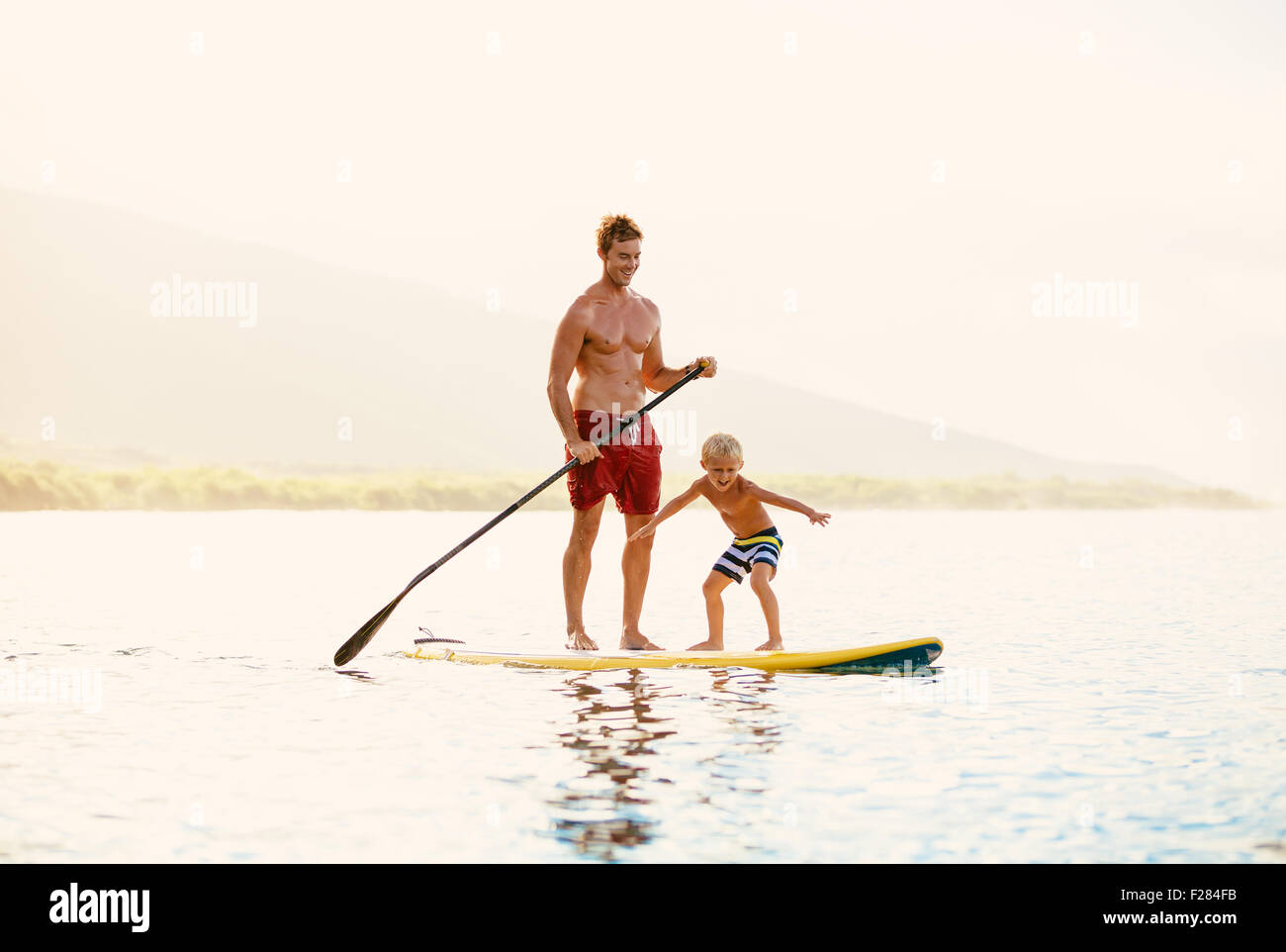 Father and Son Stand Up Paddling at Sunrise Stock Photo