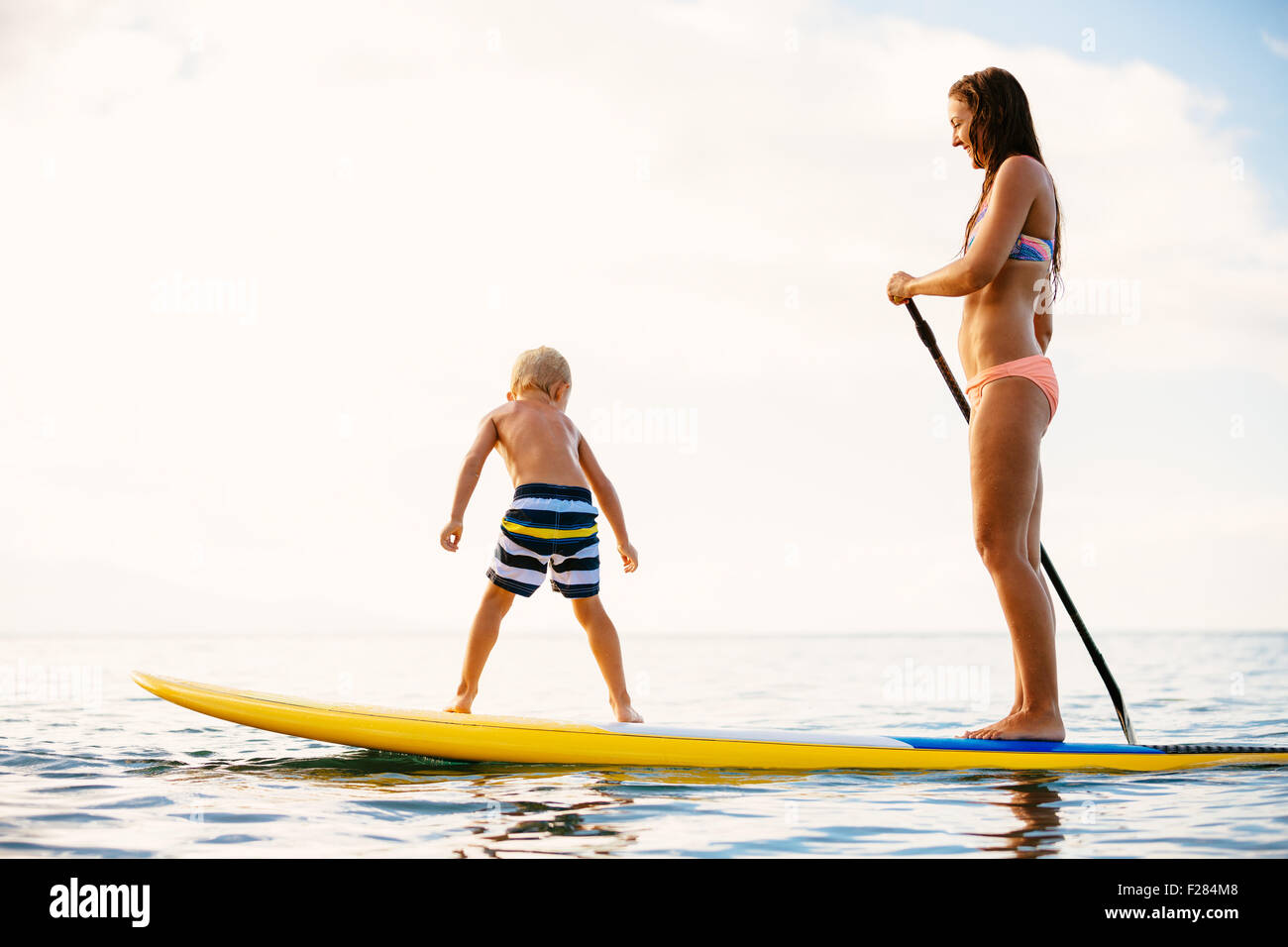 Mother and Son Stand Up Paddling Together Having Fun in the Ocean Stock Photo