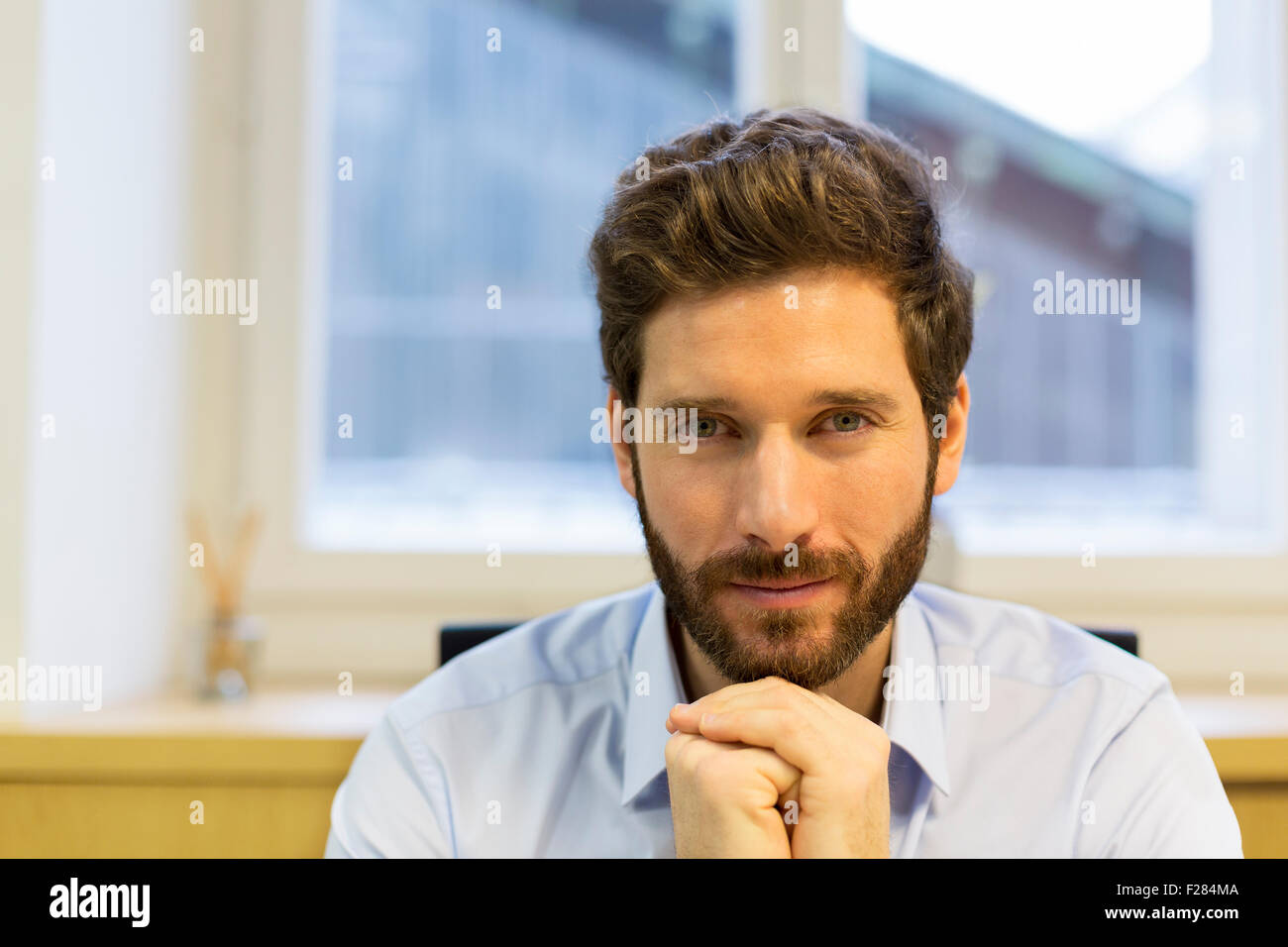 Portrait of confident bearded businessman with hands clasped Stock Photo