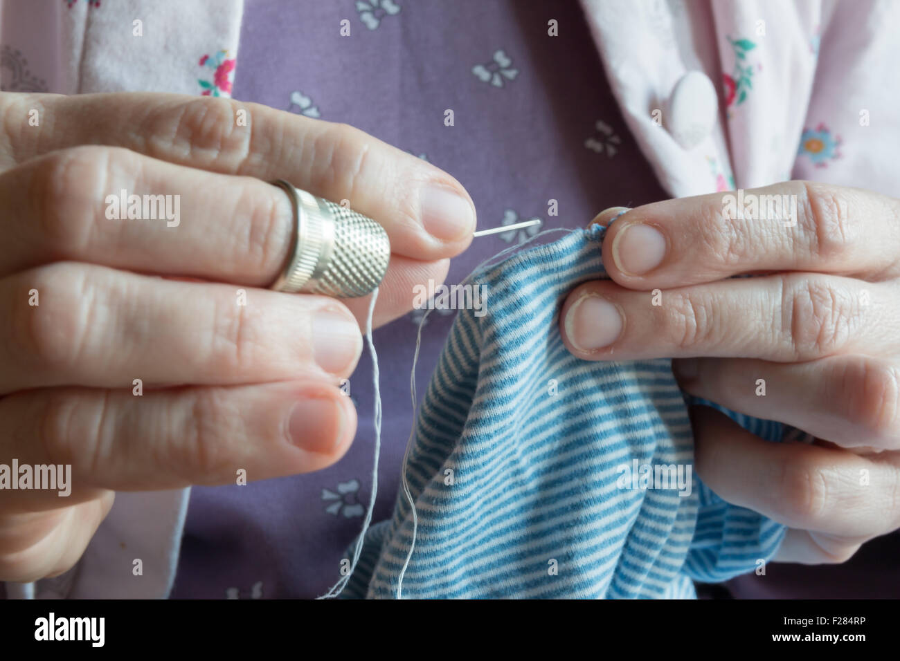 hemming a dress, woman hands needlework, detail of sewing hand Stock