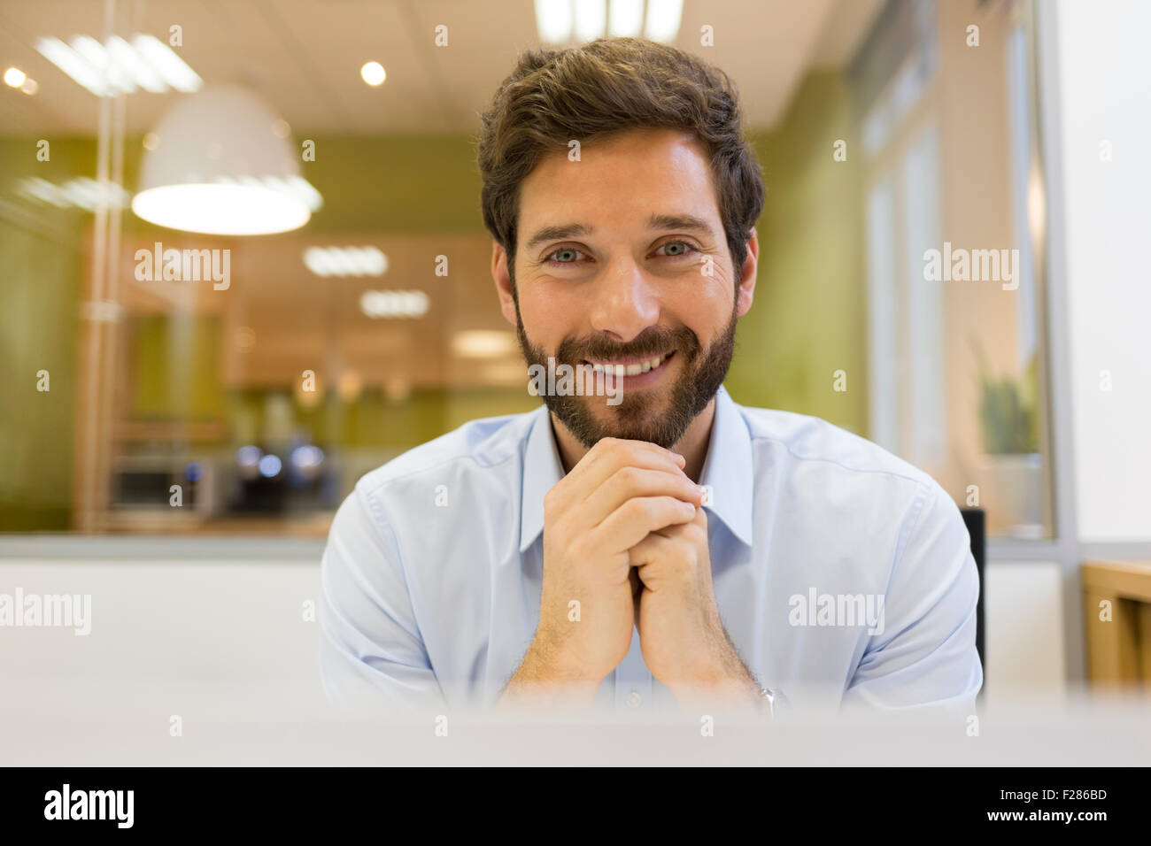 Portrait of confident bearded businessman in office with hands clasped Stock Photo