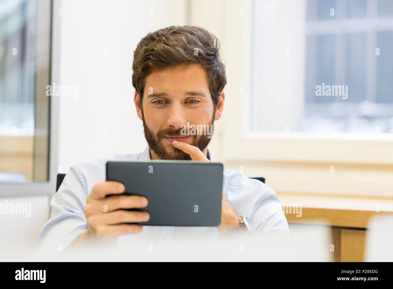 pensive businessman in office using digital tablet Stock Photo