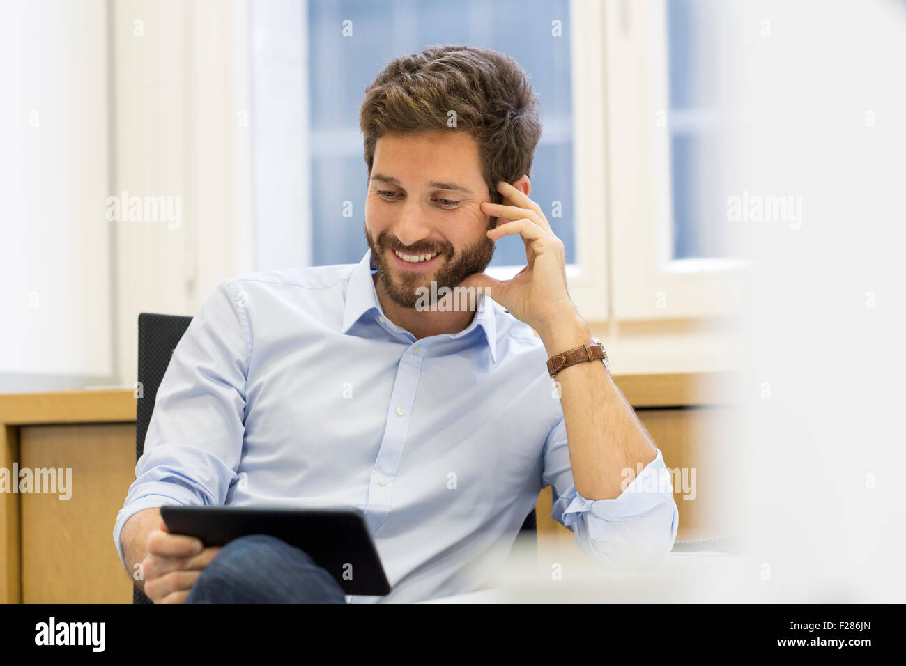 Cheering businessman in office using digital tablet Stock Photo