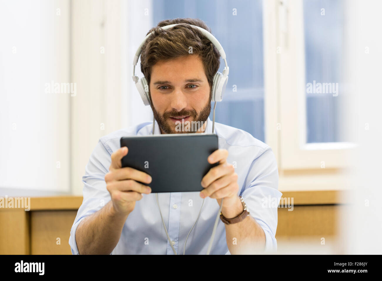 Creative businessman listening to headphones and using digital tablet. Stock Photo