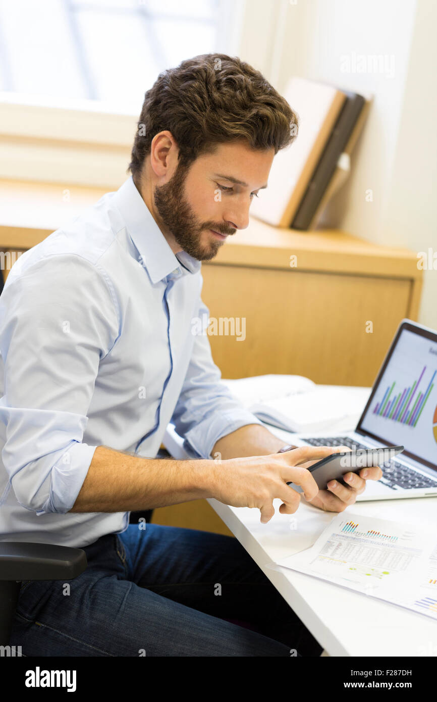 Young bearded businessman in office consulting tablet computer. Stock Photo