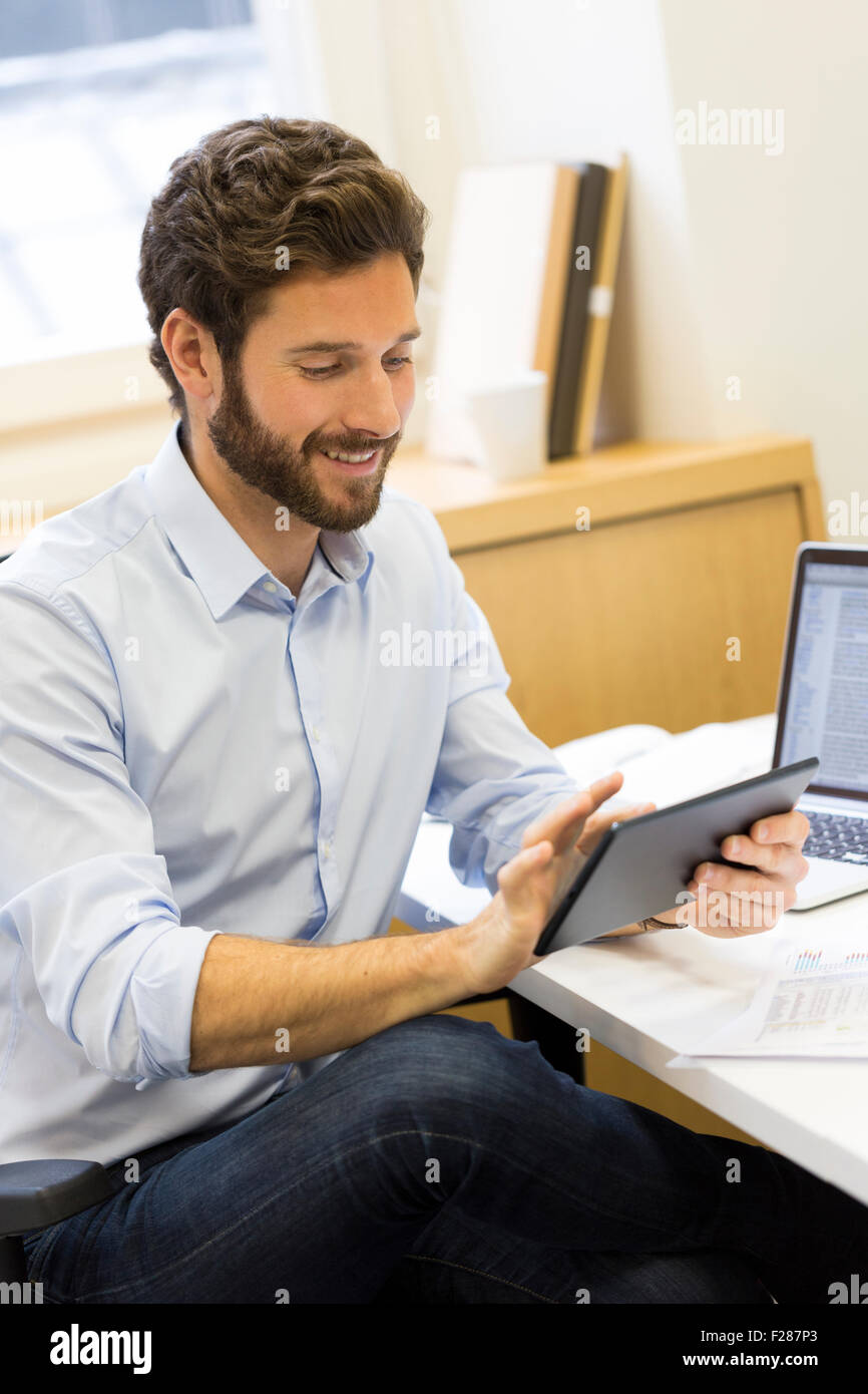 Young bearded businessman in office consulting tablet computer. Stock Photo