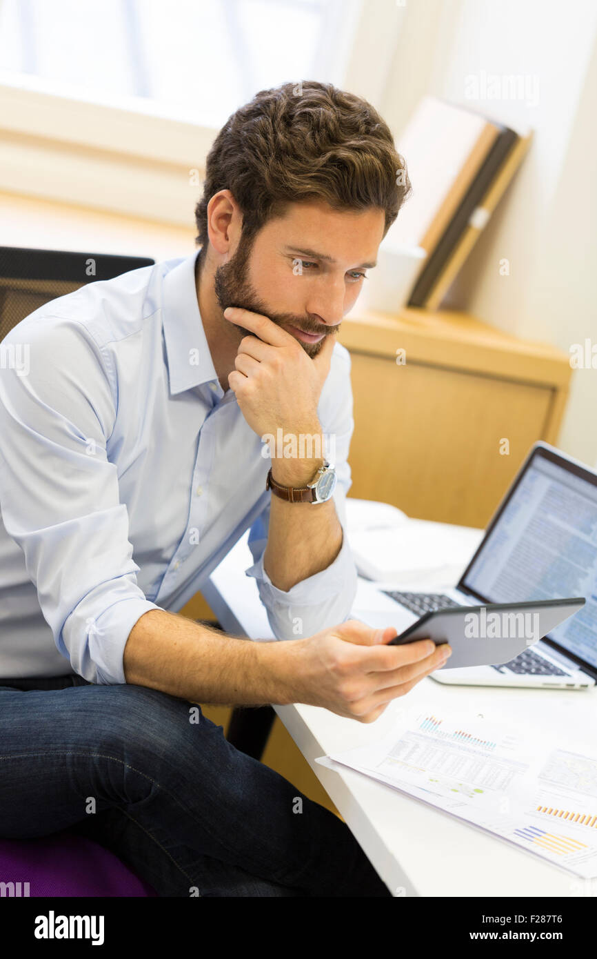 Young bearded businessman in office consulting tablet computer. Stock Photo