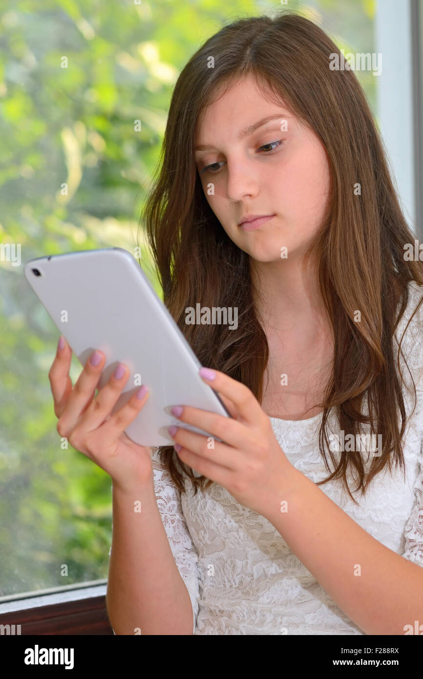 Serious attractive young girl reading information on a tablet computer Stock Photo