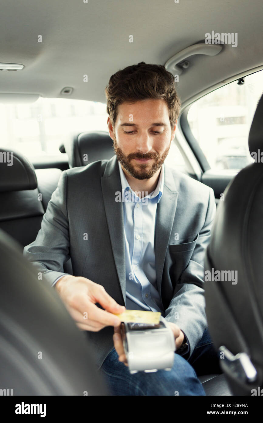 Man paying the taxi with the credit card. NFC technology Stock Photo