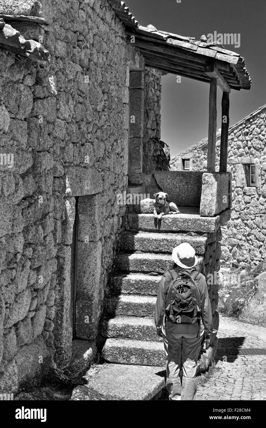Portugal: Woman looking to dog at the staircase of a stone house in the historic village Monsanto (bw) Stock Photo