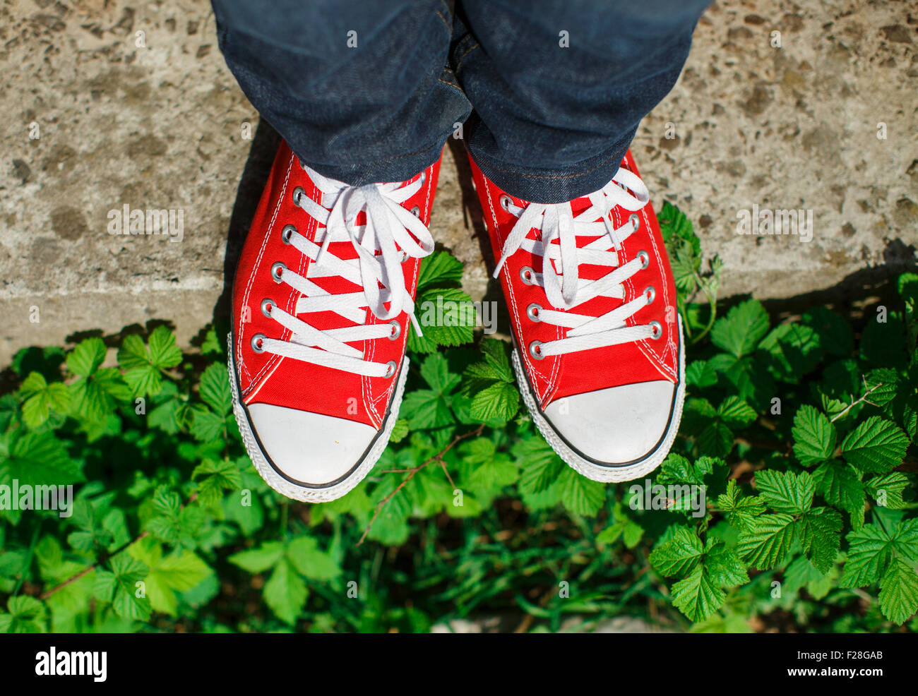 Red sneakers shoes on concrete among bushes top view, soft-focus Stock  Photo - Alamy
