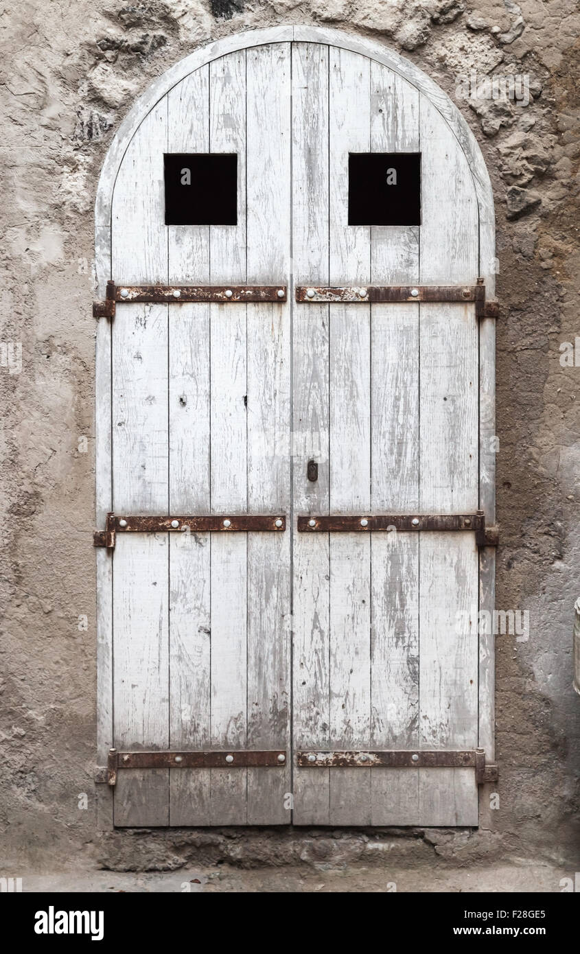 Old white wooden door with arch in old stone wall, background texture Stock Photo