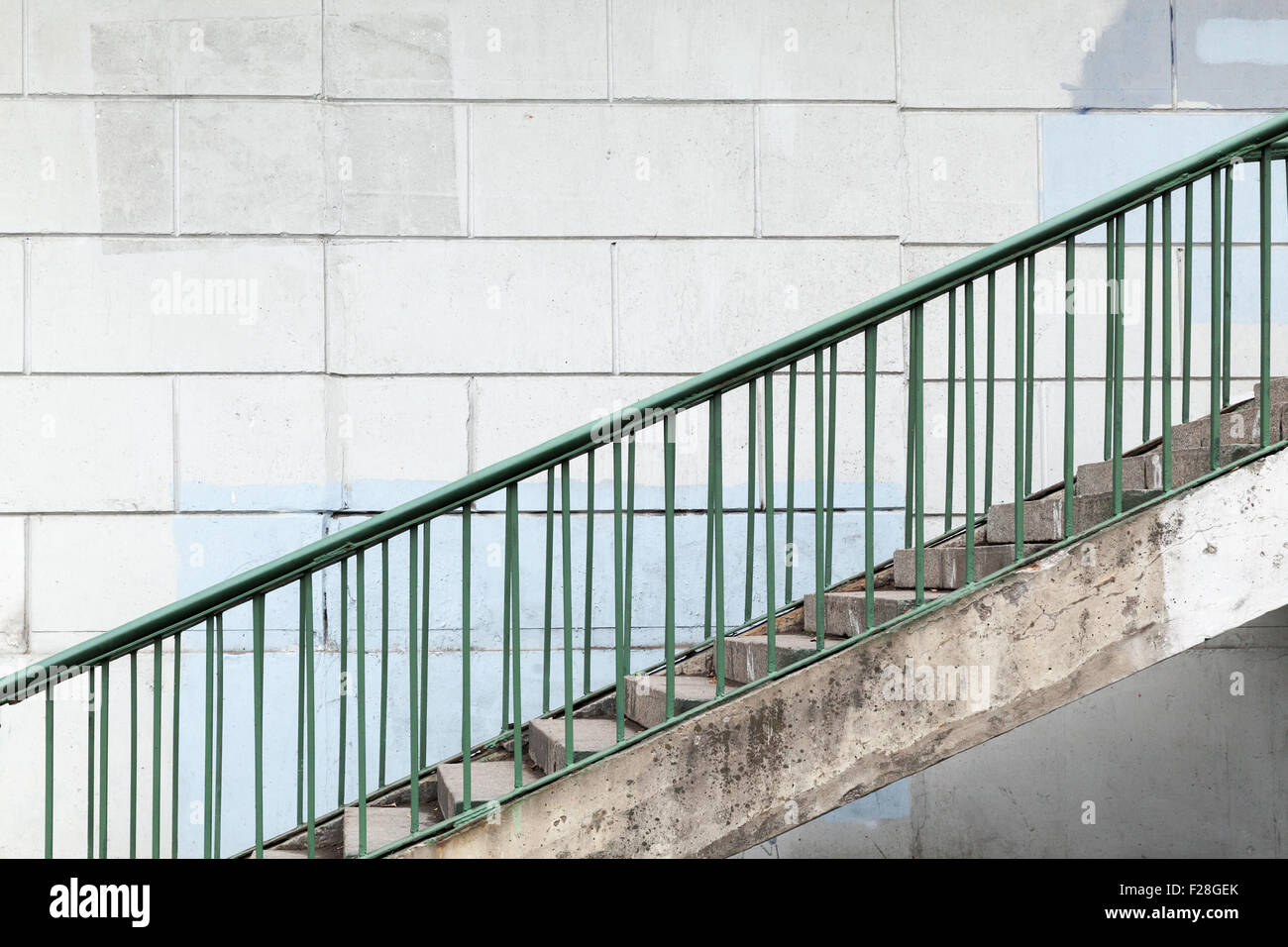 Urban stairway with green metal railings over white concrete wall Stock Photo