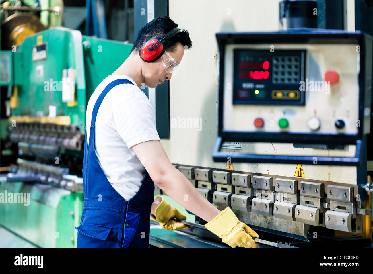 Asian machine operator in production plant checking data Stock Photo