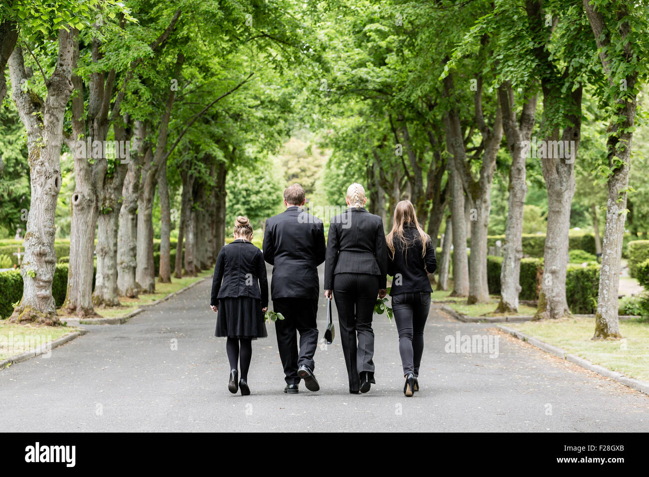 Family walking down alley at graveyard Stock Photo