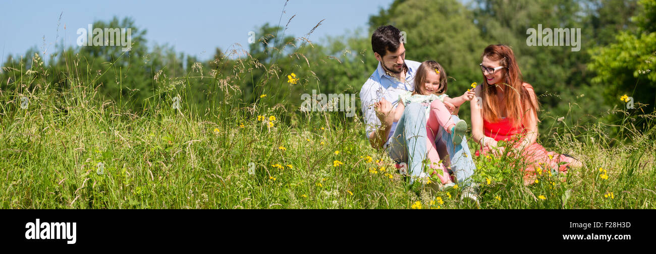 Panorama picture of family with mom, dad and daughter on meadow Stock Photo