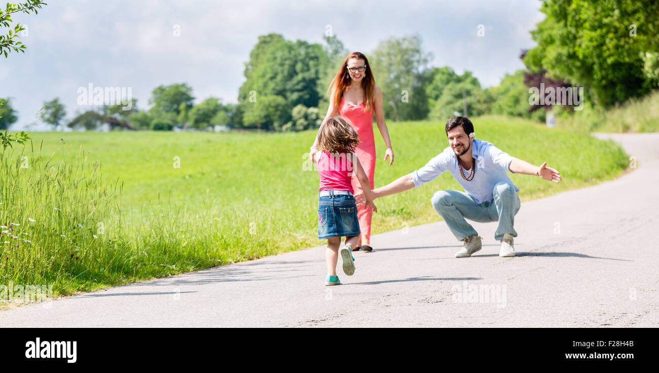 Mom, dad and daughter having walk on path in summer Stock Photo