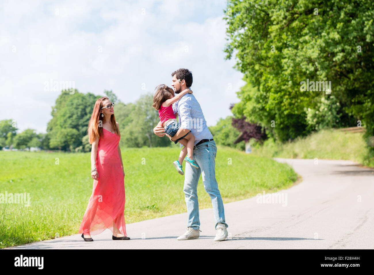 Mom, dad and daughter having walk on path in summer Stock Photo