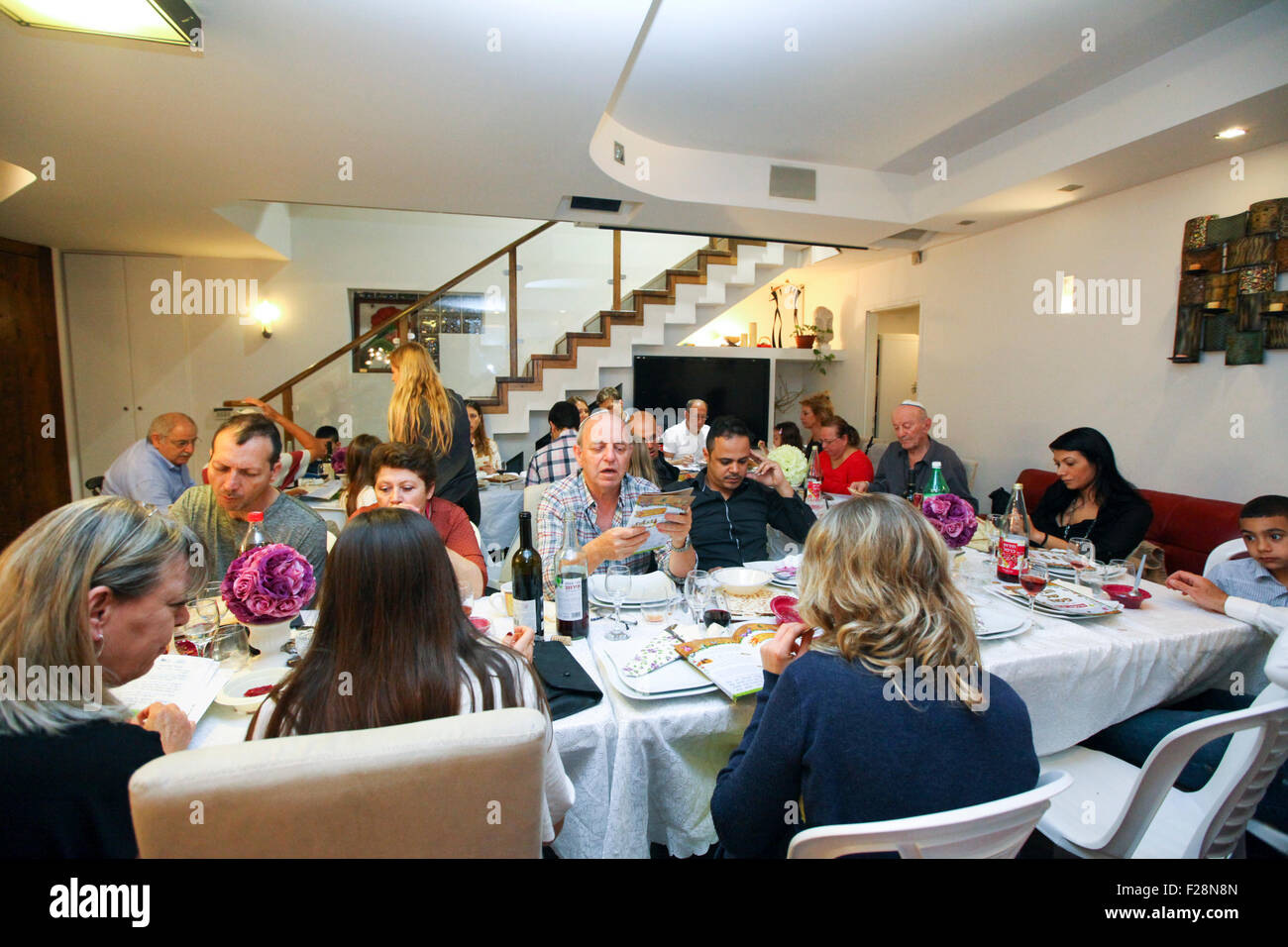 family sitting around a table set for a Jewish Festive meal on Passover (transliterated as Pesach or Pesah) Stock Photo