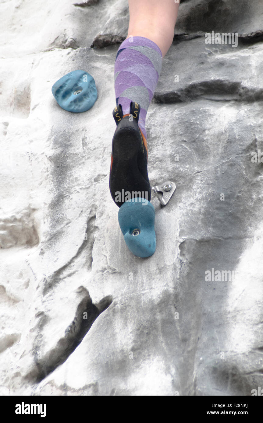 Young teen girl climbs up an artificial climbing wall close up of the feet and special climbing shoes Stock Photo