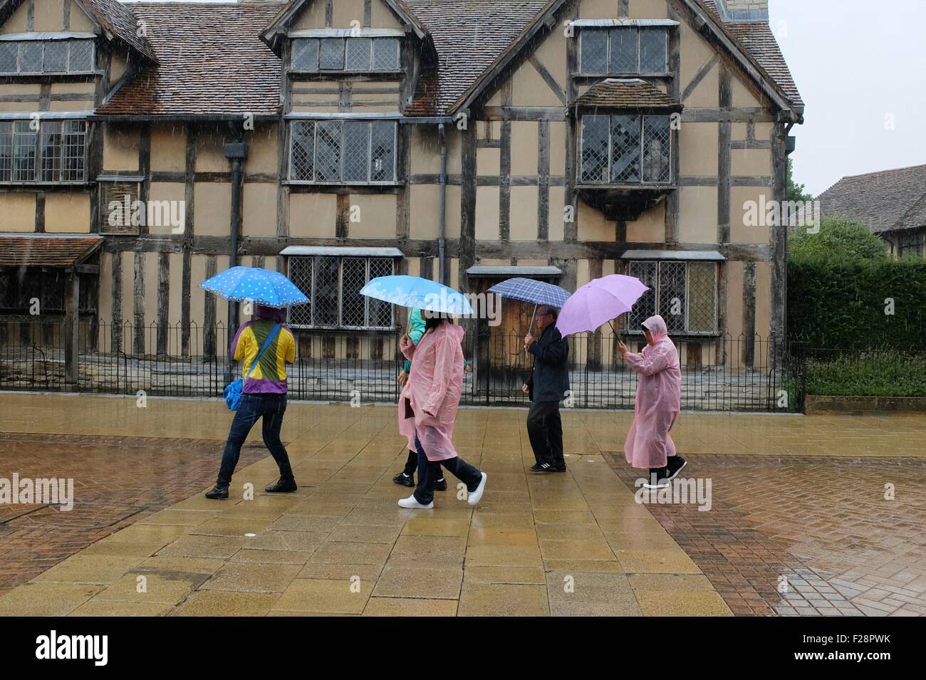 UK Weather. People get caught in heavy rain as they walk past Shakespeare's house in Stratford upon Avon: 14 September 2015 STUART WALKER Stock Photo