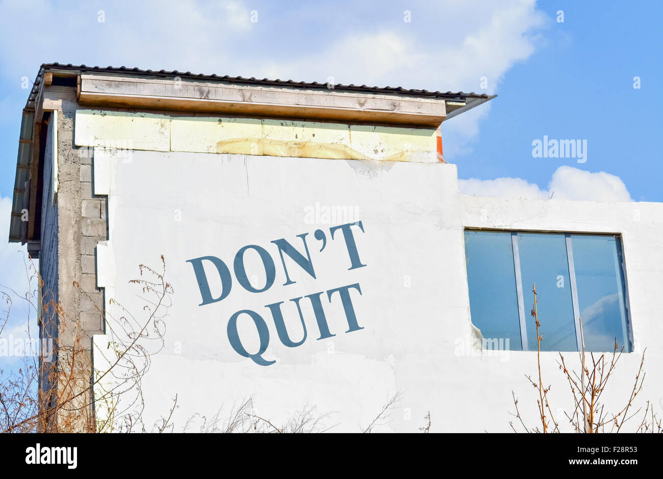 Text Do Not Quit written on the wall on an unfinished house Stock Photo