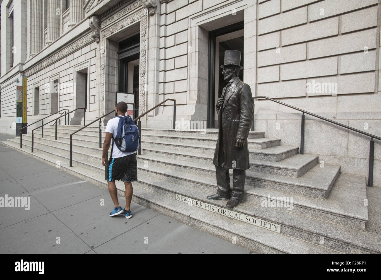 Sculpture of Abraham Lincoln on the steps of the NY Historical Society as a young African American man walks by. Stock Photo