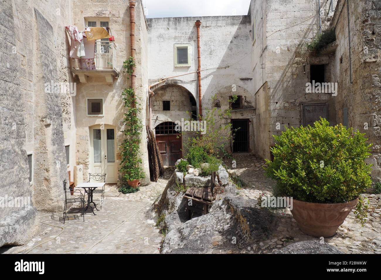 A courtyard with pot plants and a small outdoor table and chairs Stock