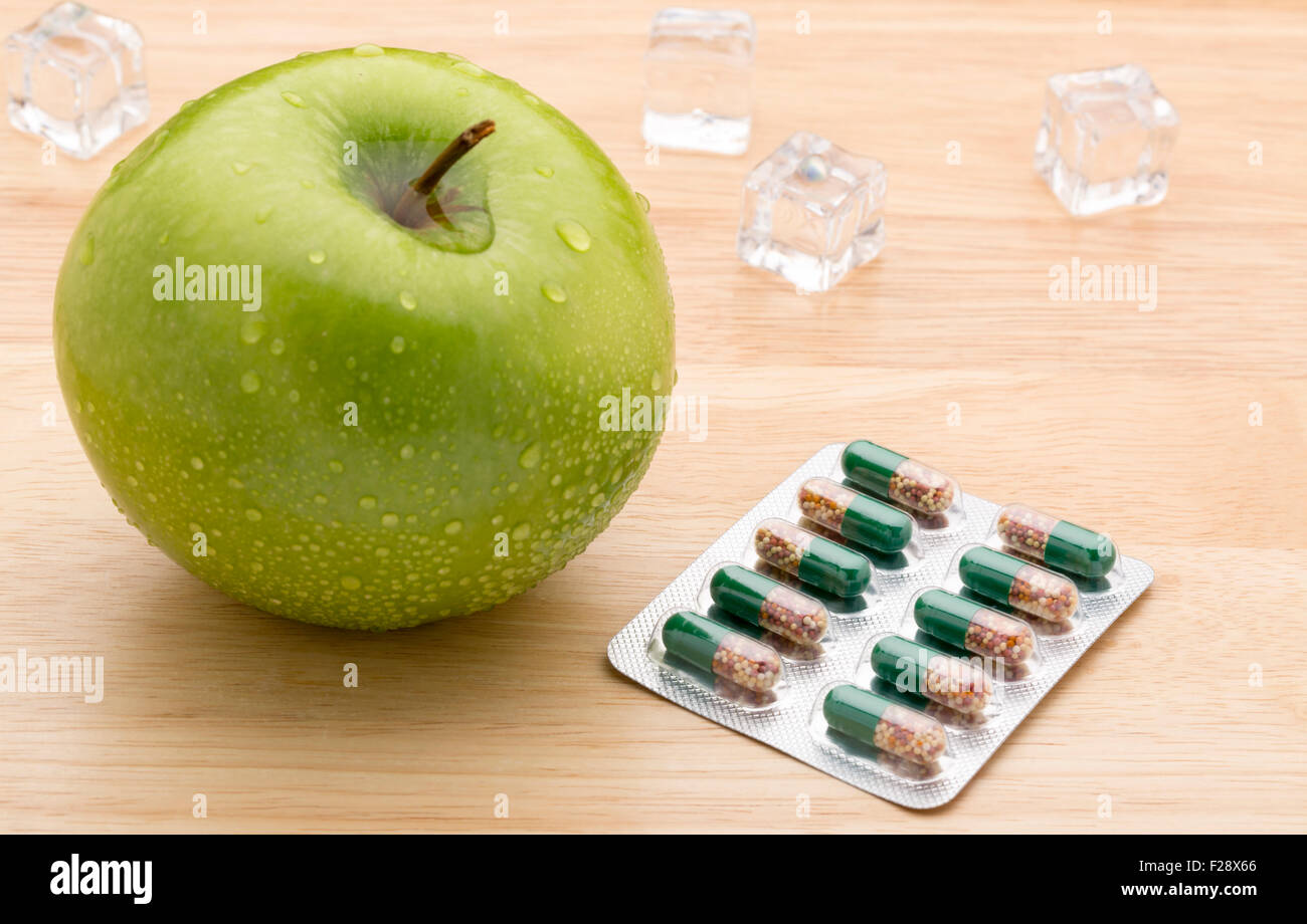 Green transparent pills capsules and fresh green apple Stock Photo