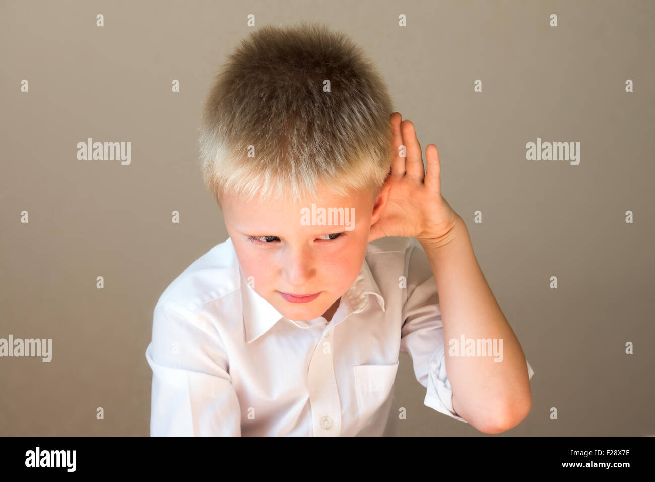 Child listening overhearing something with hand to ear concept Stock Photo