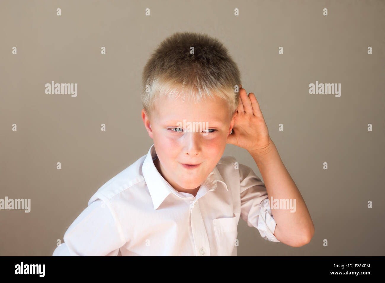 Funny child listening overhearing something with hand to ear concept Stock Photo