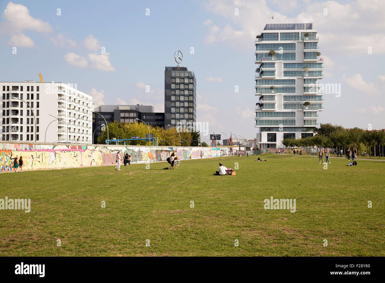 people in the former death strip at the East Side Gallery with a new luxury apartment block behind, Berlin, Germany Stock Photo
