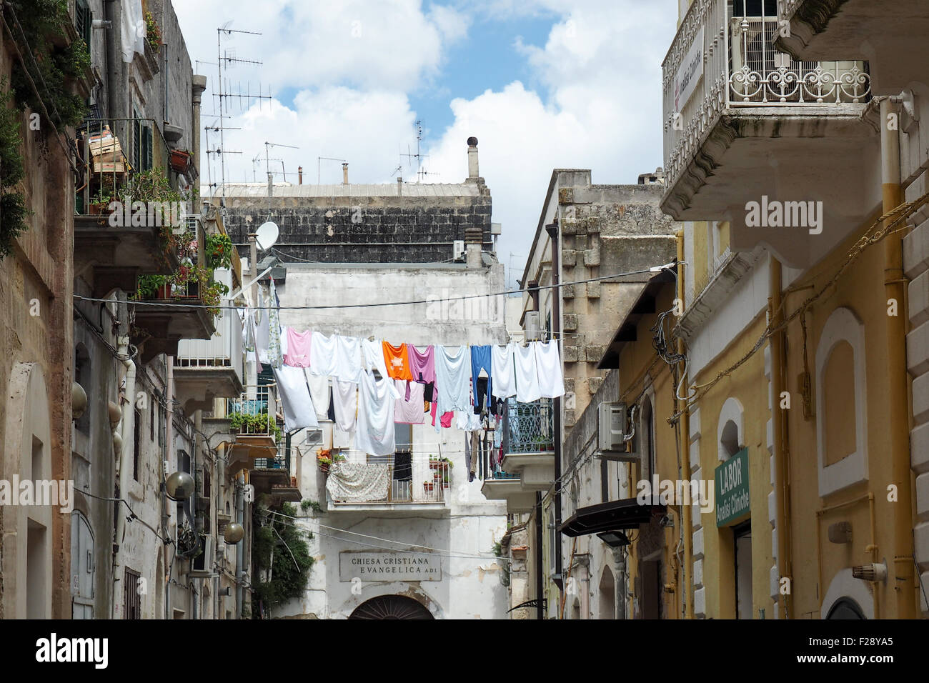 Clothes hanging out to dry on a clothesline across a street in Matera. Stock Photo