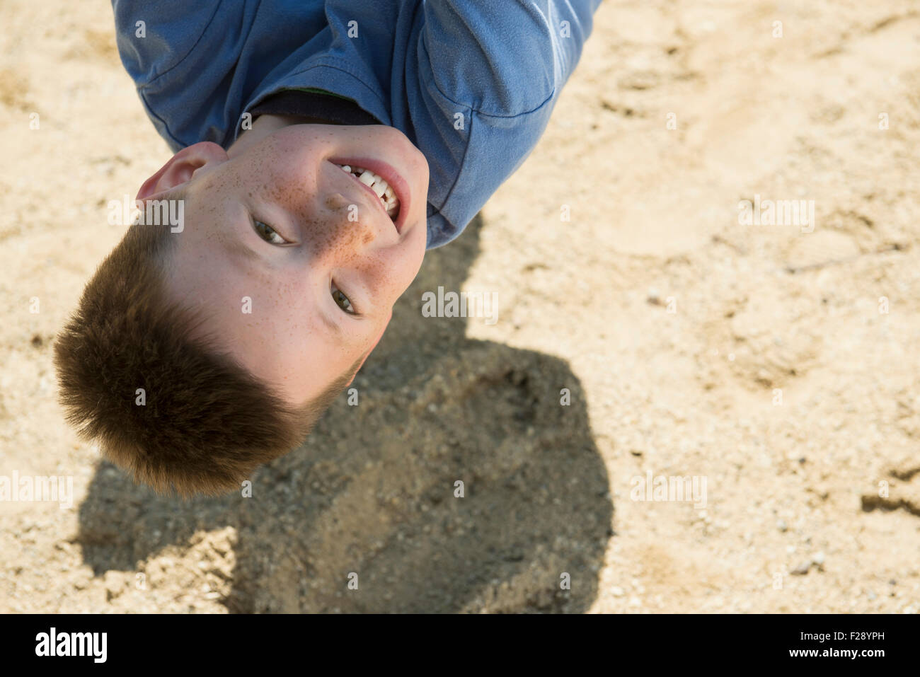 Boy hanging upside down from rope in playground, Munich, Bavaria, Germany Stock Photo