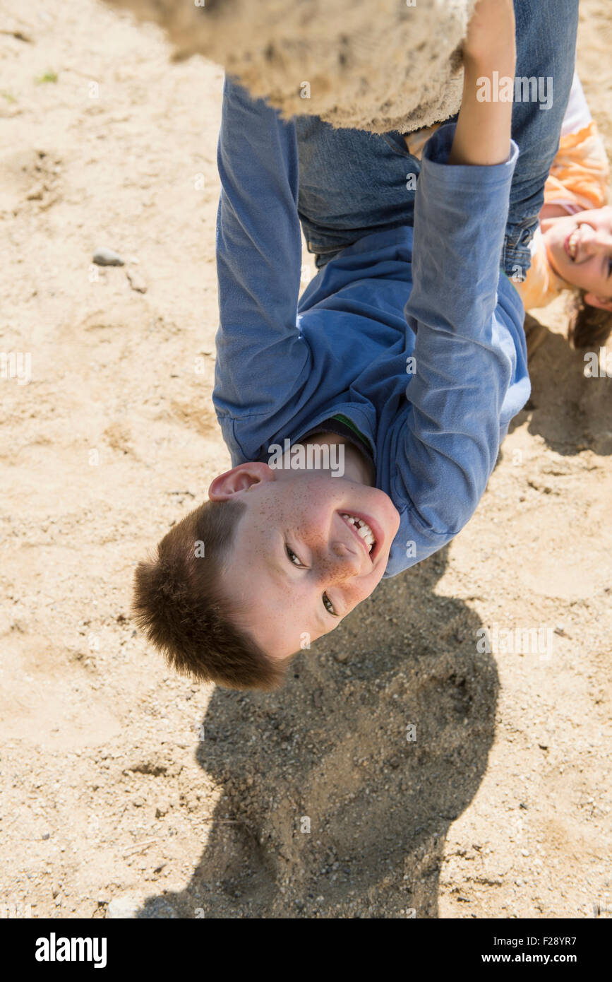 Boy and girl hanging upside down from rope in playground, Munich, Bavaria, Germany Stock Photo