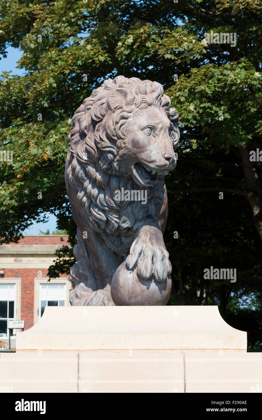 Statue of a roaring male lion on a plinth in front of the Art Deco tea room and café in Stanley Park, Blackpool, Lancashire Stock Photo