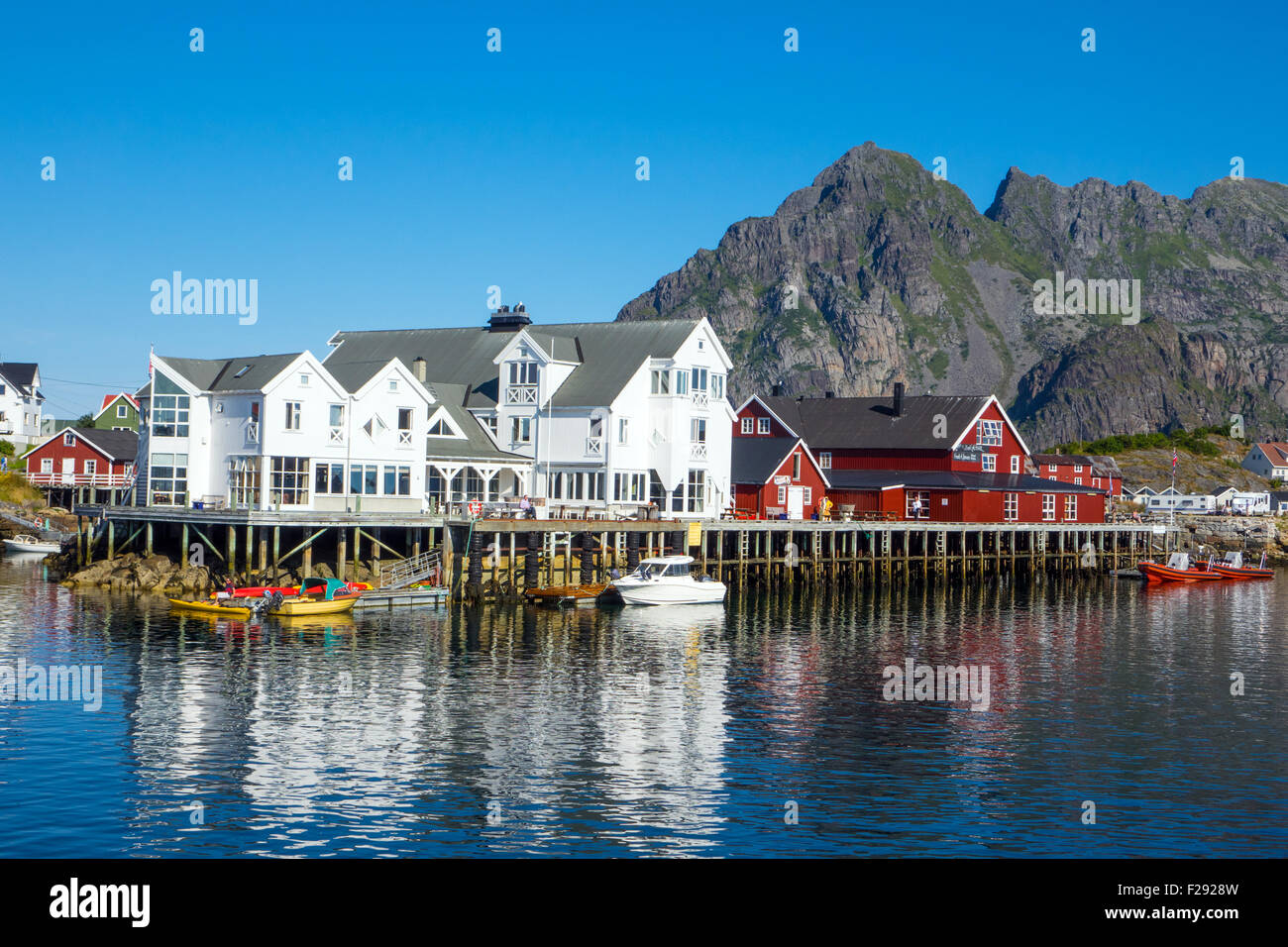 Red and white waterside fishing houses, Rorbu, on wooden stilts, with reflections Stock Photo