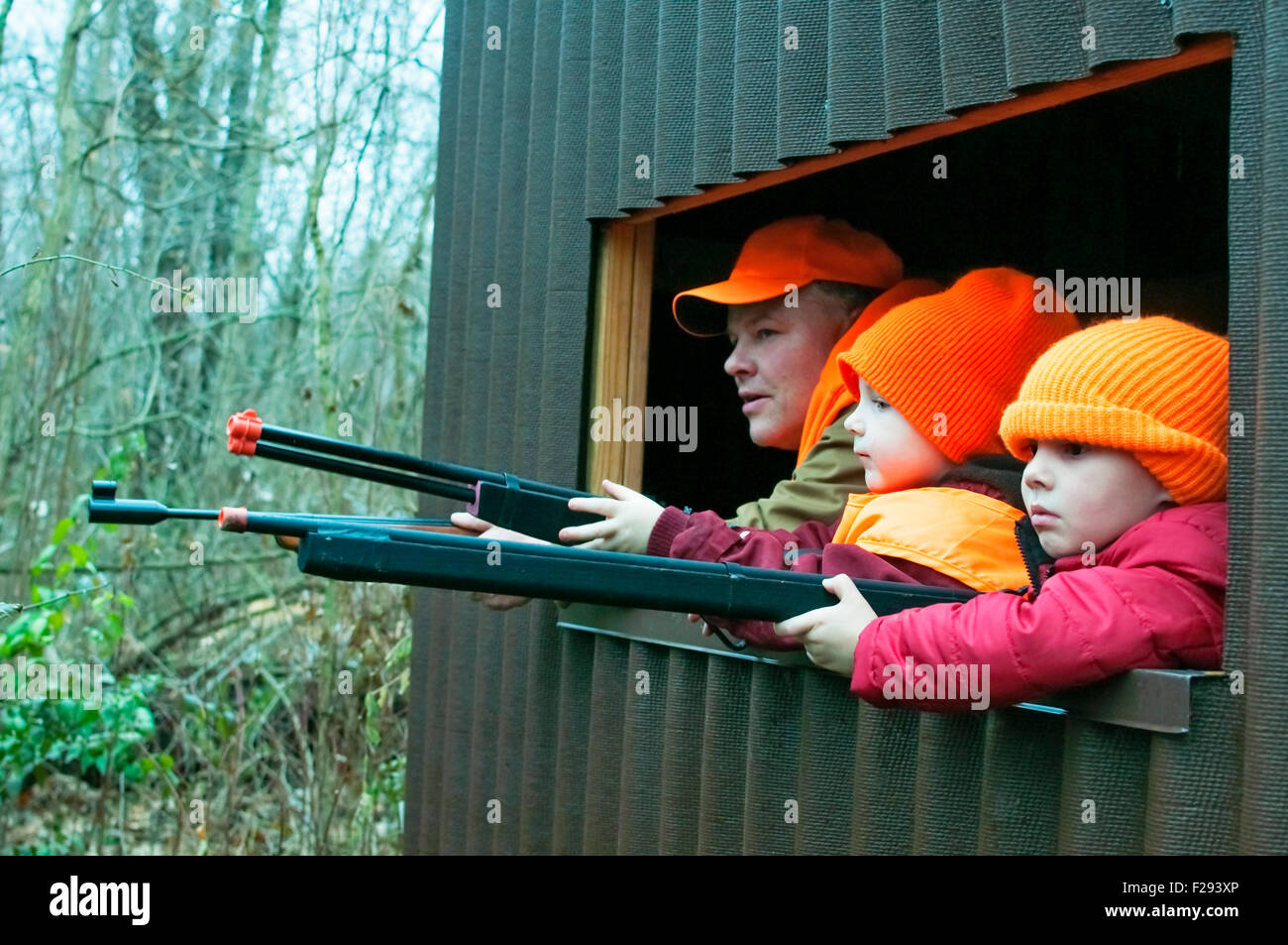 Dad teaching boys on practice hunt in deer stand Stock Photo