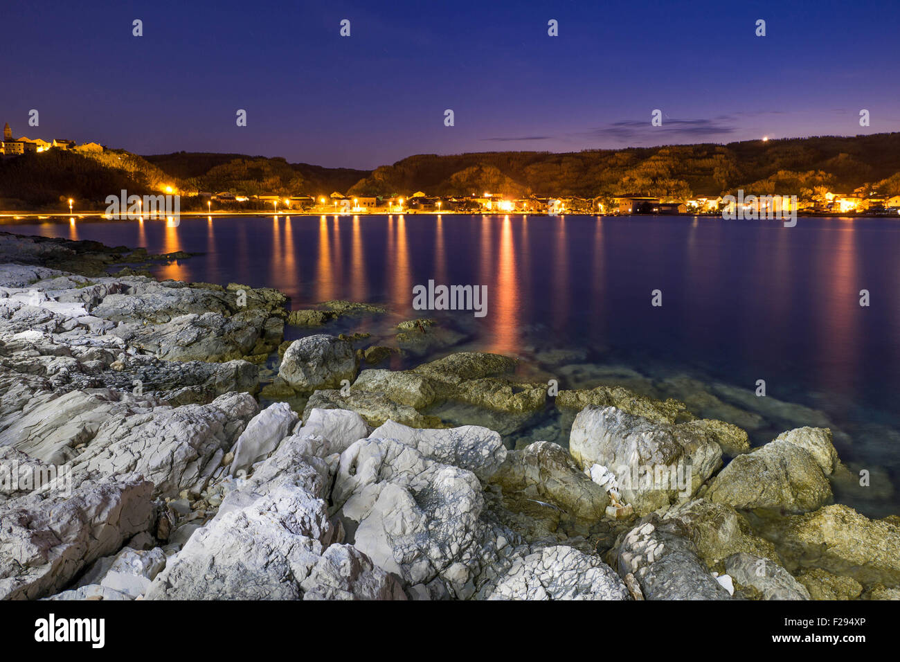Coast of Susak at night, lights reflecting in the water Stock Photo