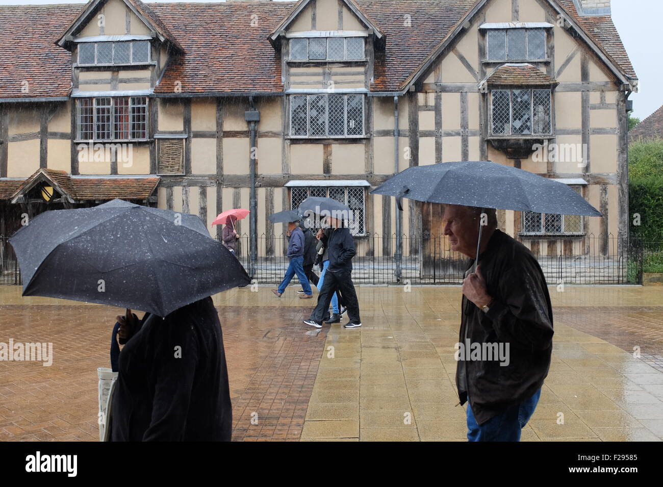 UK Weather. People get caught in heavy rain as they walk past Shakespeare's house in Stratford upon Avon: 14 September 2015.  Stock Photo
