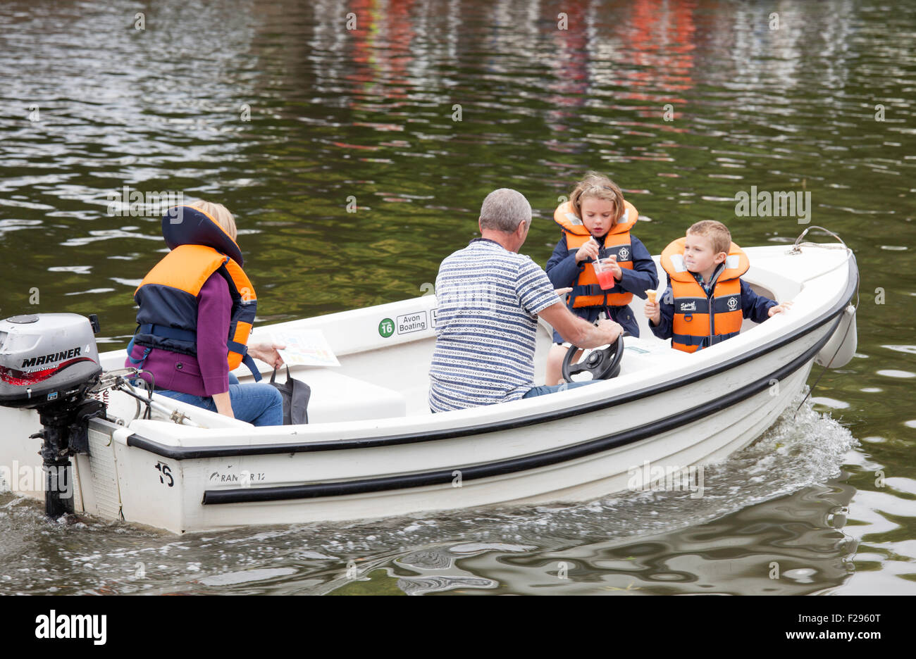 Family in a hired motorboat all wearing life jackets except the male, on the River Avon, Warwickshire, England, UK Stock Photo