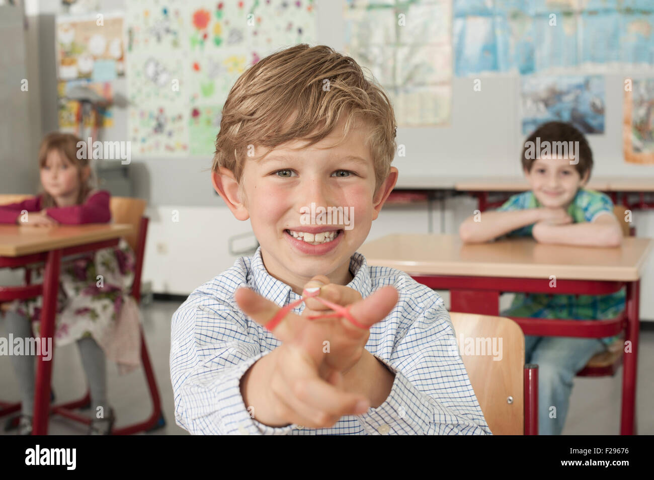 schoolboy with a slingshot and smiling in classroom, Munich, Bavaria, Germany Stock Photo